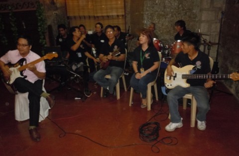 Ha, the ASEAN participant from Vietnam, strums the electric guitar with passion; The band at Kapitan Moy Café in Marikina City is at the background